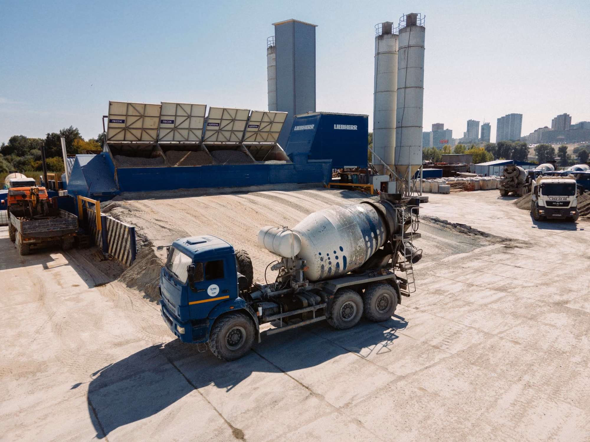 Camion toupie devant une centrale à béton, ses trémies à granulats et ses silos à ciment